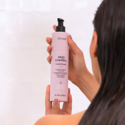 mujer sosteniendo el acondicionador de Teknia Frizz Control