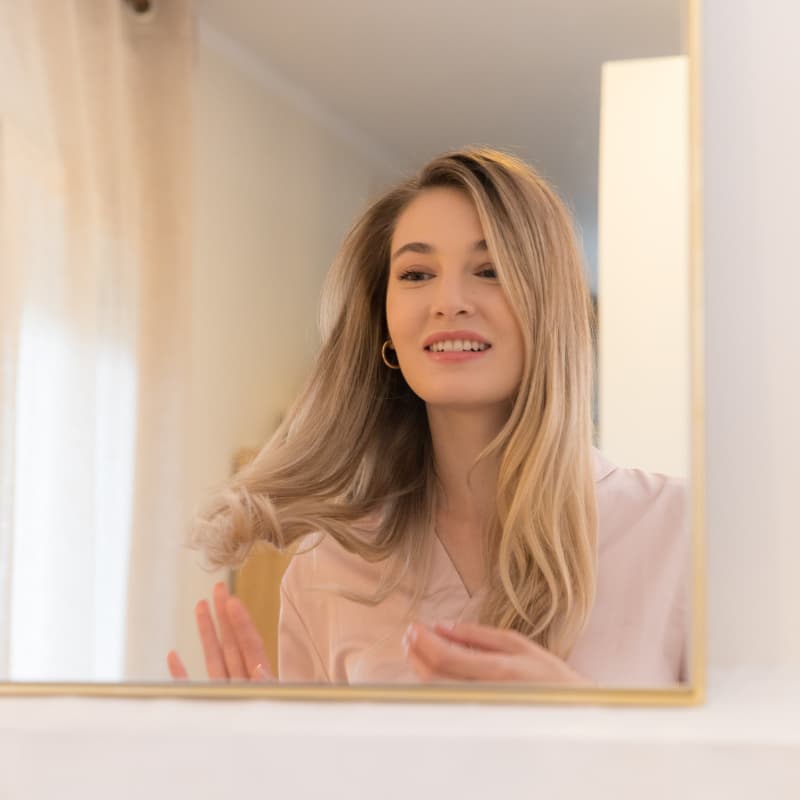 mujer de pelo rubio mir&aacute;ndose al espejo