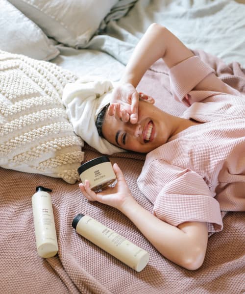 mujer tumbada en la cama con los productos Teknia Deep Care
