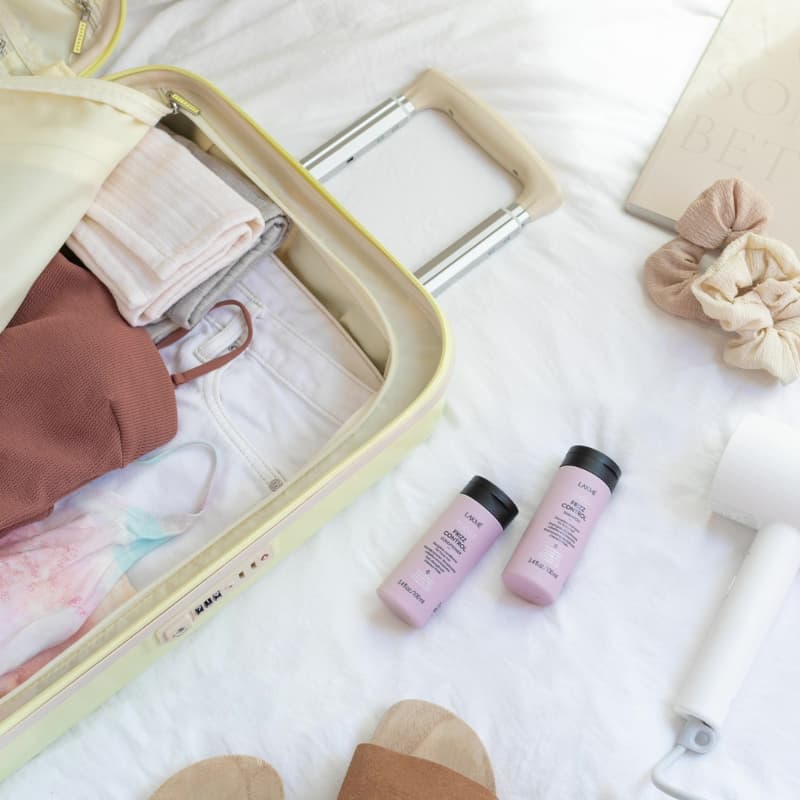 maleta de viaje junto a productos de la gama Teknia Frizz Control